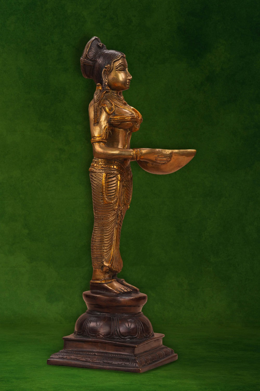 Image of A brass and copper woman holding a diya