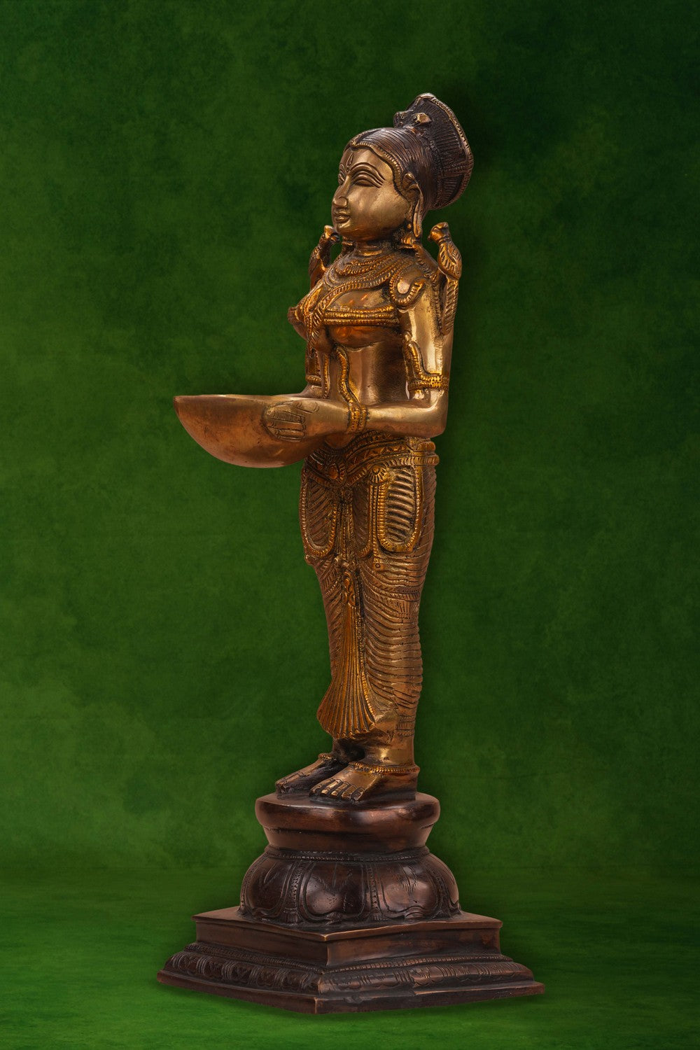 Image of A brass and copper woman holding a diya